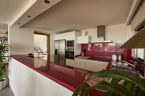 A modern kitchen with a red countertop, stainless steel appliances, and a red backsplash. - Villa Aitana with jacuzzi - My Rental Homes (Playa De Talamanca)