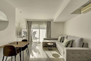 A modern living room with a sofa, a dining table, and a TV. - Villa Aitana with jacuzzi - My Rental Homes (Playa De Talamanca)