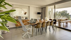 Een moderne eetruimte met een grote tafel, stoelen en een laptop.