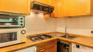A compact kitchen with a stove, microwave, and built-in oven. - Campicioi by Interhome (Pinzolo)