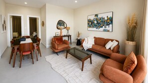 A living room with a sofa, armchairs, a coffee table, and a dining area with chairs and a table. - CMH SARL (Mbour)