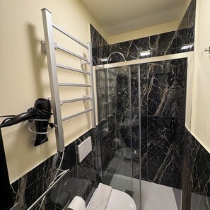 Une salle de bain moderne avec une douche à parois de verre, un porte-serviettes et un sèche-cheveux.