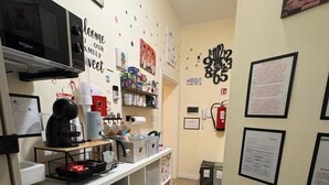 A kitchen area with a coffee machine, shelves with various items, and a wall clock. - Room & Brerakfast Nel Cuore di Faenza (Faenza)