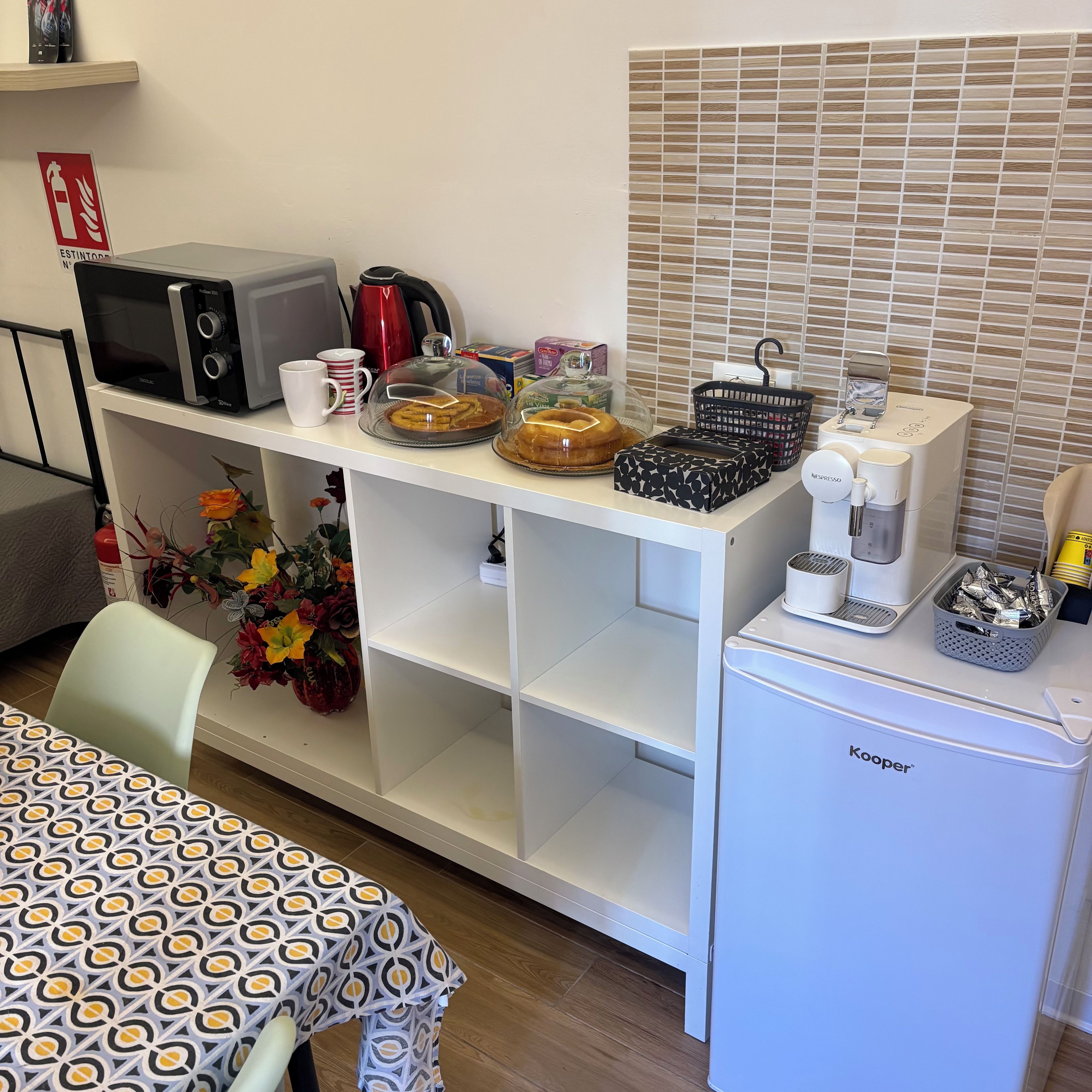 A kitchenette with a microwave, kettle, coffee maker, and a small fridge.