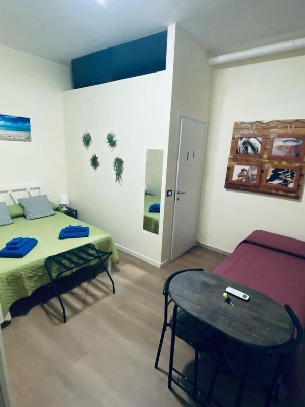 Une pièce avec un lit, une petite table, un miroir et une porte.