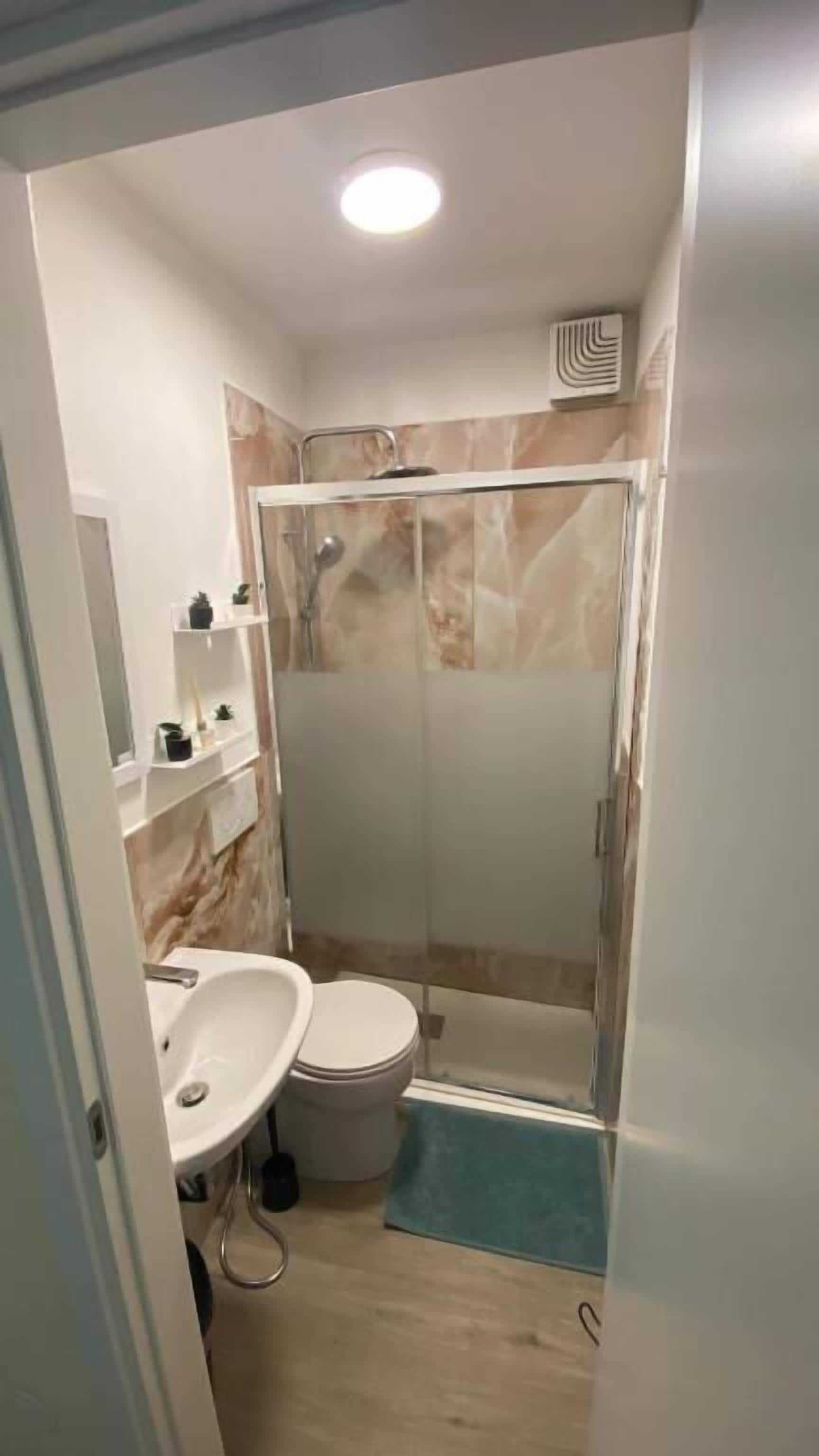 A bathroom with a shower, toilet, and sink.