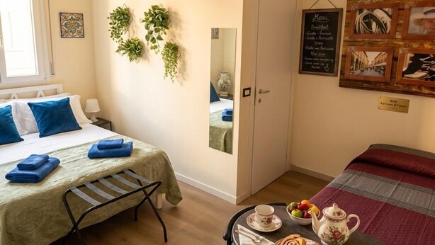 A room with a bed, a table with breakfast items, a mirror, and a wall with framed pictures. - Room & Brerakfast Nel Cuore di Faenza (Faenza)