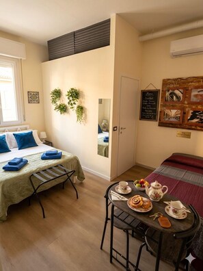 Une chambre avec un lit, une table avec des éléments pour le petit-déjeuner, un miroir et un mur orné de tableaux.