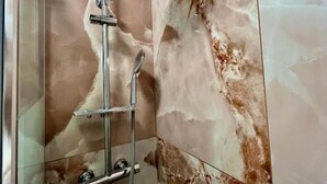 A shower with a handheld showerhead and a wall-mounted faucet in a bathroom with marble walls. - Room & Brerakfast Nel Cuore di Faenza (Faenza)