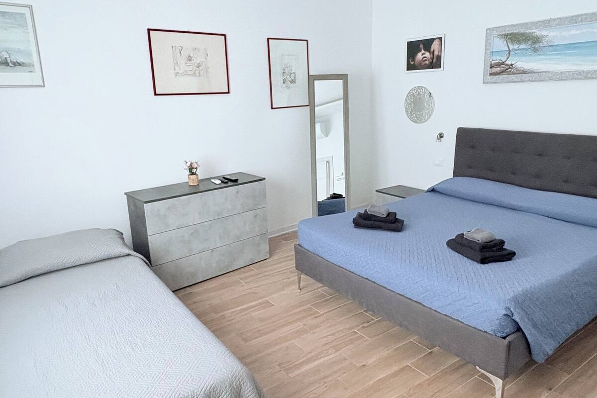 Ein Schlafzimmer mit einem Bett, einem Schminktisch, einem Spiegel und Bildern an den Wänden.