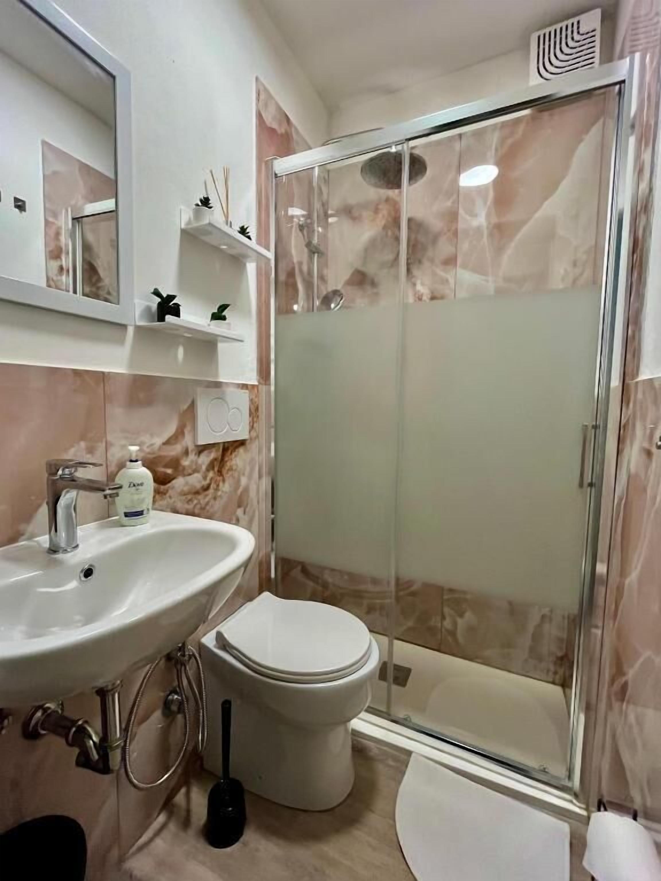 A bathroom with a sink, toilet, and glass-enclosed shower.