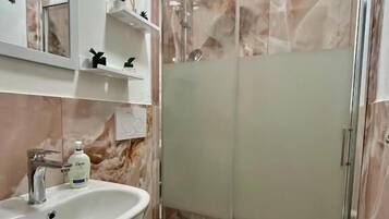 A bathroom with a sink, toilet, and glass-enclosed shower.