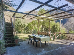 An outdoor patio with a table set for dining, surrounded by a wooden pergola structure. - Casa dei Nonni by Interhome (Stazzema)