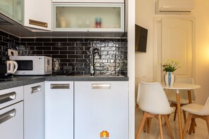 A compact kitchen with a microwave, toaster, and sink. There is a dining area with a table and chairs. -  ✨ Mamma Mia Stay – Your relaxing escape in the heart of Cagliari.Imagine waking up in the center of Cagliari, with sunlight streaming through the window and the city ready to welcome you.Welcome to Mamma Mia Stay, a cozy apartment designed to make yo (Cagliari)
