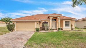 A single-story house with a tiled roof, a garage, and a well-maintained lawn. - Retreat Charmz (Kissimmee)