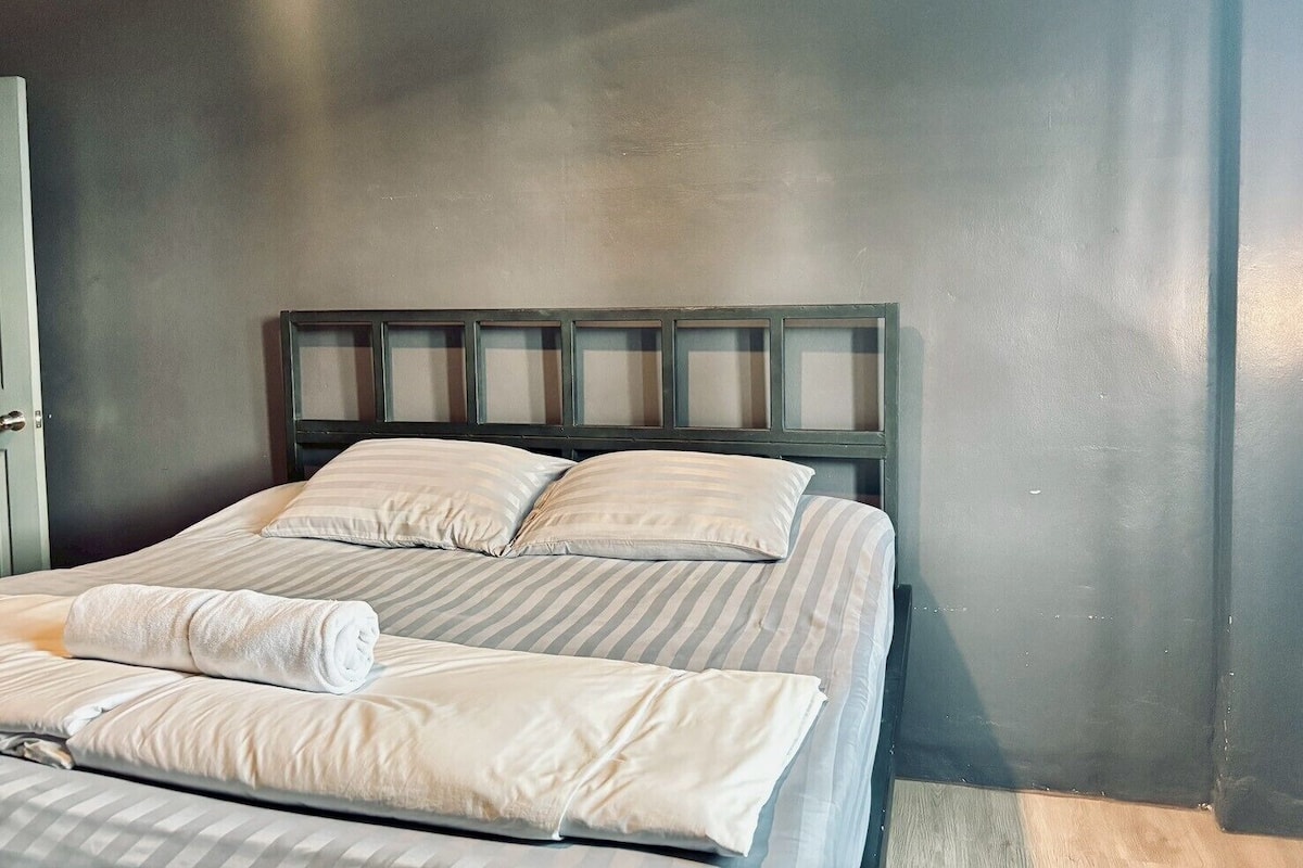 Un lit avec une tête de lit, des oreillers et une serviette enroulée.