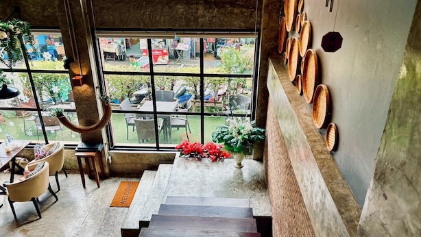 Una escalera conduce a un balcón con vistas a la calle, un felpudo y una pared con cuencos de madera.