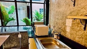 Una cocina con un lavamanos, un microondas y una ventana con plantas afuera.