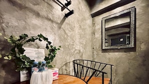 Una habitación con una mesa de madera, una silla, un espejo y una pared con textura.