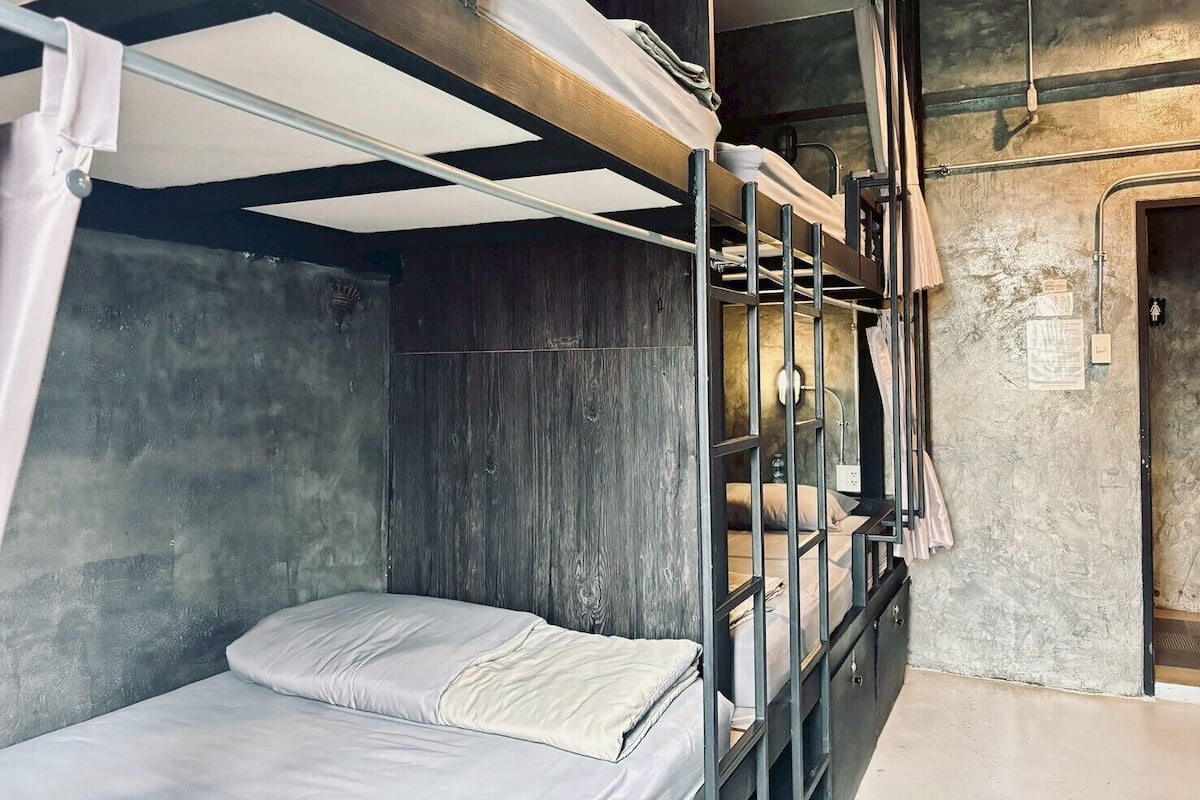 Une chambre avec un lit superposé, un mur en bois, une petite fenêtre et une porte.