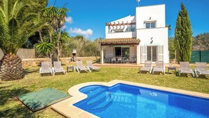 Una casa moderna de dos pisos amb piscina, seients exteriors i una pèrgola.