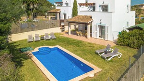 Eine moderne Villa mit Swimmingpool, Sitzgelegenheiten im Freien und einem eingezäunten Garten.