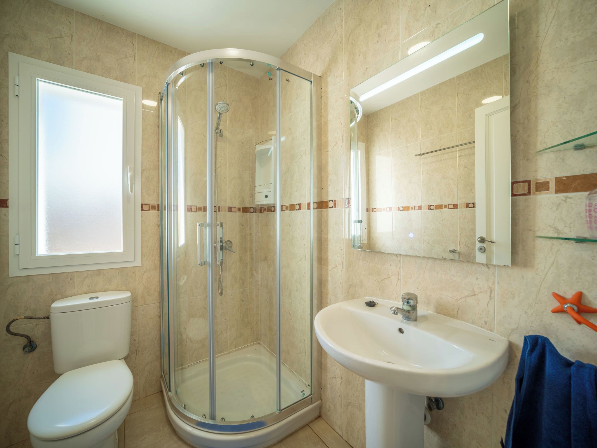 Ein Badezimmer mit einer Duschkabine, einem weißen Waschbecken und einer Toilette.