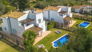 Eine moderne Villa mit Swimmingpool, mehreren Balkonen und einem üppigen Garten.