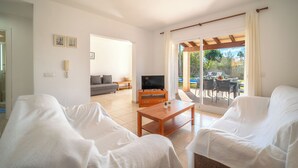 A living room with a sofa, a TV, and a table. There is a balcony with a view of the outdoors. - Son Ganxo I by Interhome (Cala Murada)