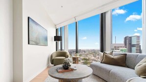 A modern living room with a large window, a round coffee table, a sofa, and a chair. - The Story Suite! 2Bed/2Bath/2Car/Pool/VIEWS ~ CBD (Brisbane City)