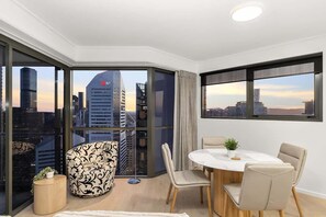 A modern room with a city view, a round dining table, and a corner sofa. - Amazing! 2Bed/2Bath/1Car/Balcony/Views ~ CBD (Brisbane City)