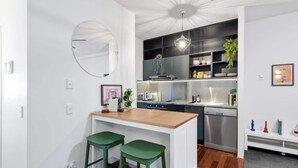 A modern kitchen with a central island, bar stools, a built-in oven, and a dishwasher. - Trendy Teneriffe! ~ 1Bed, 1Bath, 1Car, Balconies (Teneriffe)