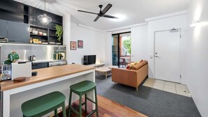 A modern kitchen with a bar area, a sofa, and a television. - Trendy Teneriffe! ~ 1Bed, 1Bath, 1Car, Balconies (Teneriffe)