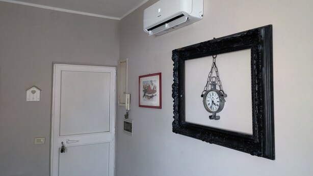 Ein Zimmer mit einer weißen Tür, einer Klimaanlage, einer gerahmten Uhr und einem kleinen Bild an der Wand.