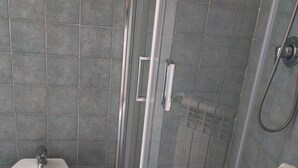 Ein Badezimmer mit einer Duschkabine, einem weißen Waschbecken und einem Handtuchhalter.