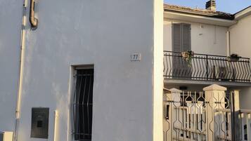 Un edificio con due finestre, una base in pietra e un cancello in metallo.