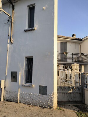 Un bâtiment doté de deux fenêtres, d’un socle en pierre et d’un portail en métal.
