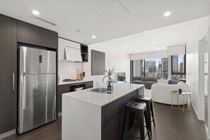 A modern kitchen with a central island, stainless steel appliances, and a city view. - Fab! Skyline CBD views over South Bank! (South Brisbane)
