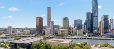 A city skyline with modern high-rise buildings, a river, and a bridge.