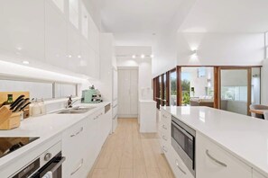 Eine moderne Küche mit weißen Schränken, einem eingebauten Backofen und einer großen Arbeitsplatte.
