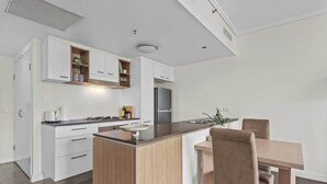 Eine moderne Küche mit weißen Schränken, einer zentralen Kücheninsel und einem Essbereich mit Tisch und Stühlen.