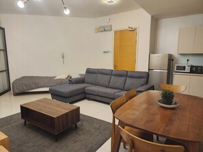 A modern living room with a grey sectional sofa, a wooden coffee table, and a dining table with chairs. A small potted plant is on the dining table. - 4r2b/1200sf/walk to bukitbintang klcc trainstation (Kuala Lumpur)
