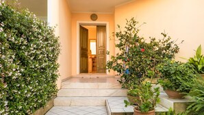 Un escalier menant à une pièce dotée d’une porte, le tout entouré d’une végétation luxuriante et de plantes en pot.