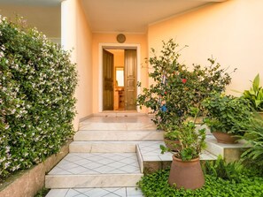 A staircase leading to a room with a door, surrounded by lush greenery and potted plants. - Vacation home Papaia by Interhome (Tortolì)