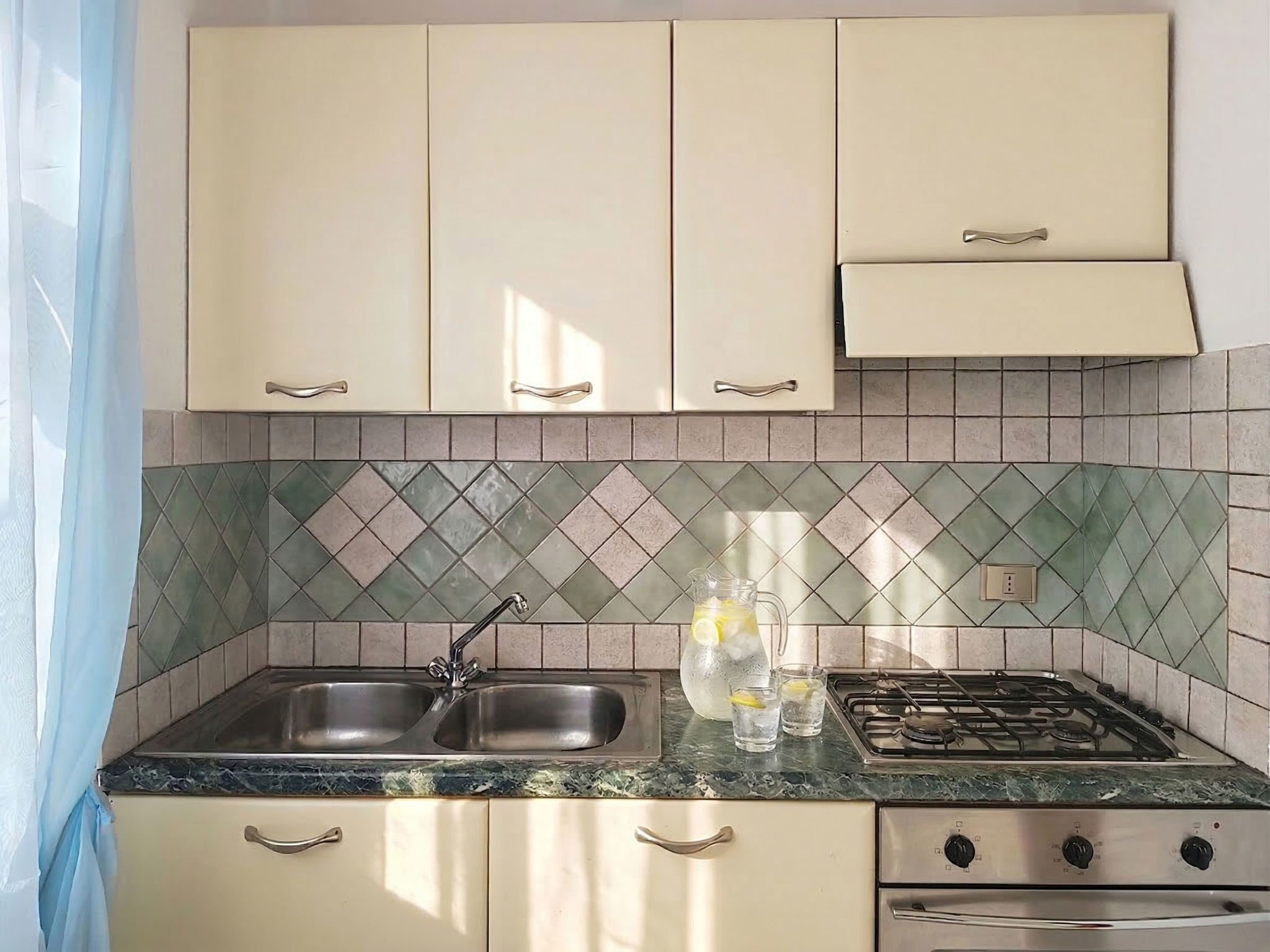 A kitchen with two sinks, a gas stove, and a cabinet with a handle.