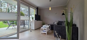 A modern living room with a sofa, TV, and a dining area with a table and chairs. - "Ostwind" Vacation Apartment with a Terrace and Beach Chair in Graal-Müritz (Graal-Müritz)