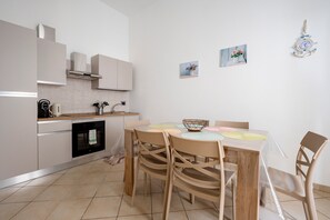 A modern kitchen with white cabinets, a dining table with chairs, and a small oven.
