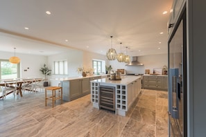 Une cuisine moderne dotée d’un grand îlot central, de meubles de rangement gris et d’un coin repas avec des meubles en bois.
