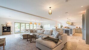 Ein geräumiger Wohnbereich mit einem großen Sofa, einem Esstisch und einer Küche im Hintergrund.
