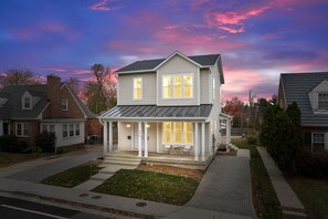 A two-story house with a covered porch and a garage. - Spacious 4BR w/ Basement Game Room • Lux Listings (Alexandria)
